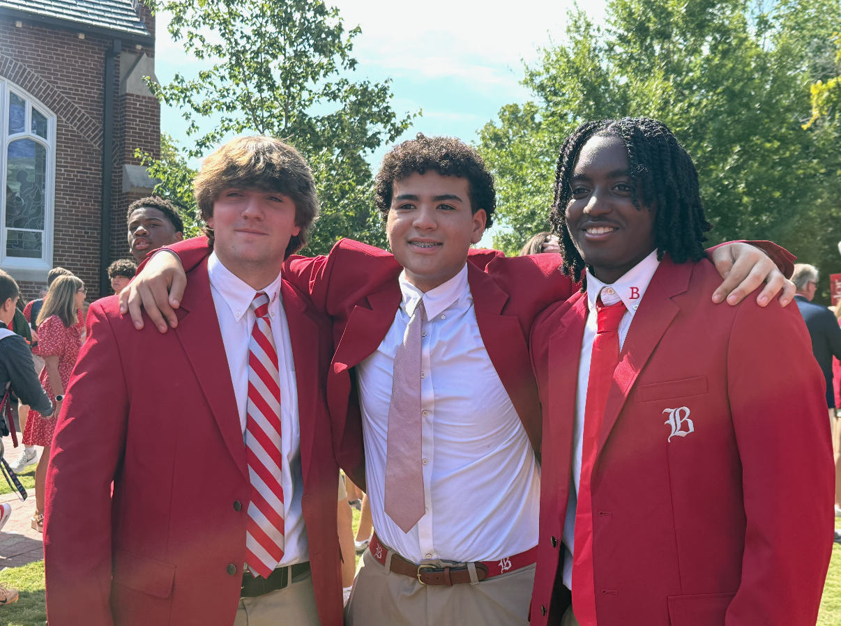 Adrian, in the middle, with two friends wearing Baylor’s senior red blazers on the chapel lawn